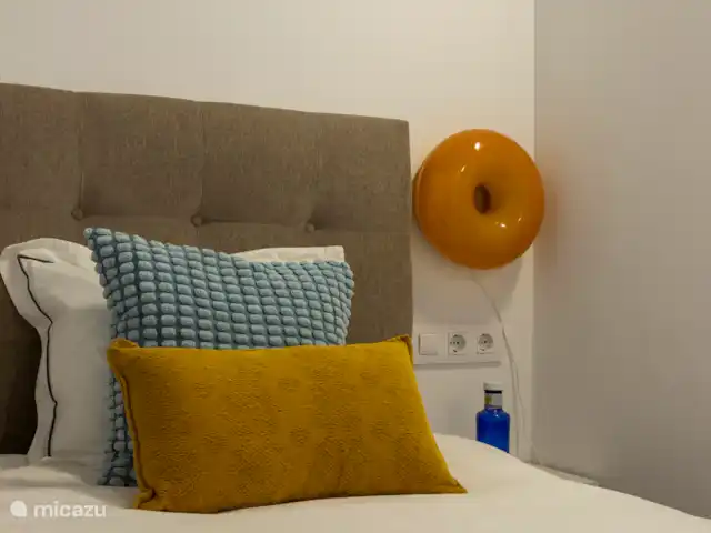 Tweepersoonskamer met kingsize bed, ladenkastje, plafondventilatir, badjassen en spiegel. Deze kamer heeft een ensuite badkamer.